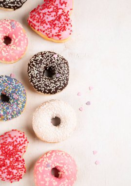 Donut deseni. Çeşit çeşit jöleli donutların üst görüntüsü. Kremalı renkli çörekler. Açık arkaplan üzerine serpiştirilmiş çeşitli renkli donutlar. Boşluğu kopyala.