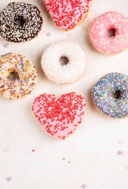 Donut deseni. Çeşit çeşit jöleli donutların üst görüntüsü. Kremalı renkli çörekler. Açık arkaplana serpiştirilmiş çeşitli renkli donutlar..