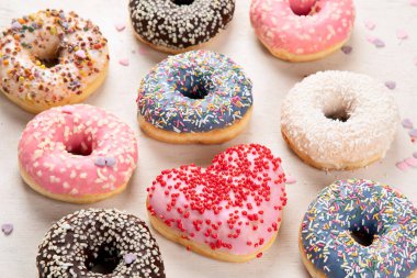 Donut deseni. Çeşit çeşit jöleli donutların üst görüntüsü. Kremalı renkli çörekler. Açık arkaplana serpiştirilmiş çeşitli renkli donutlar..