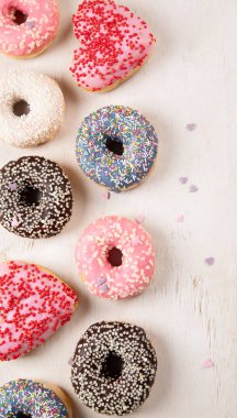 Donut deseni. Çeşit çeşit jöleli donutların üst görüntüsü. Kremalı renkli çörekler. Açık arkaplan üzerine serpiştirilmiş çeşitli renkli donutlar. Boşluğu kopyala.