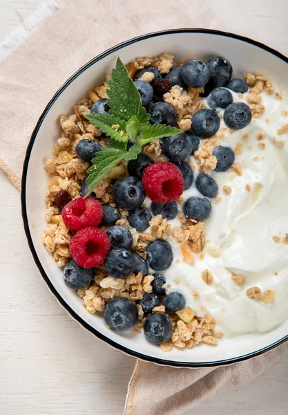 Sağlıklı kahvaltı için yoğurt ve böğürtlenli granola. Beyaz arka planda, yaban mersini ve ahududu aromalı bir kase Yunan yoğurdu..
