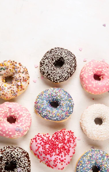 Donut deseni. Çeşit çeşit jöleli donutların üst görüntüsü. Kremalı renkli çörekler. Açık arkaplan üzerine serpiştirilmiş çeşitli renkli donutlar. Boşluğu kopyala.