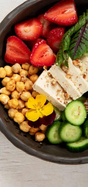 Sağlıklı vejetaryen yemek kasesi. Avokado, kinoa, salatalık, kırmızı portakal, nohut, peynir, salata ve beyaz arka planda çilek. Üst görünüm.