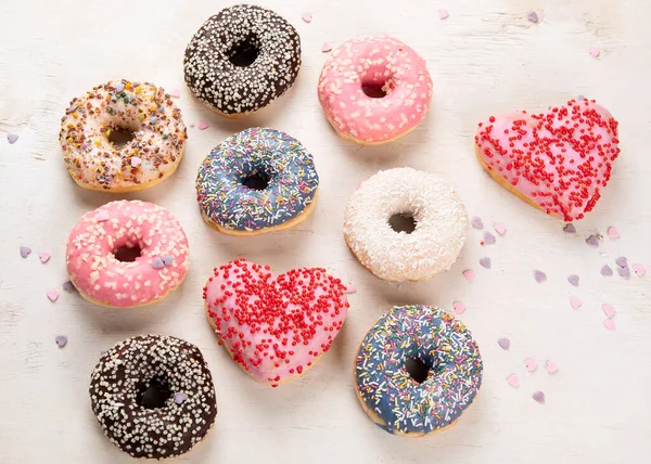 Donut deseni. Çeşit çeşit jöleli donutların üst görüntüsü. Kremalı renkli çörekler. Açık arkaplana serpiştirilmiş çeşitli renkli donutlar..