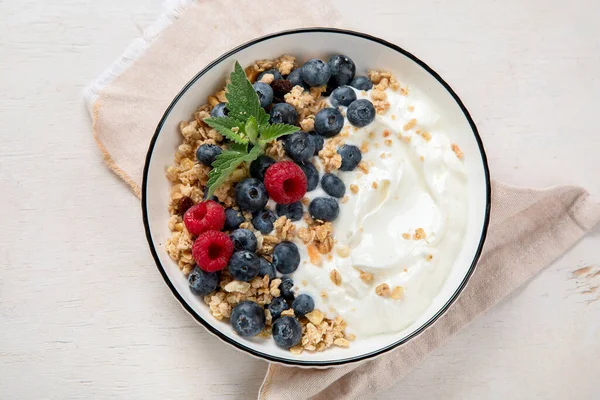 Sağlıklı kahvaltı için yoğurt ve böğürtlenli granola. Beyaz arka planda, yaban mersini ve ahududu aromalı bir kase Yunan yoğurdu..