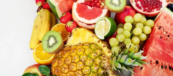 Taze meyveler, beyaz bir zemin üzerinde çeşitli meyveler. Vitaminler doğal beslenme konsepti. Panorama.