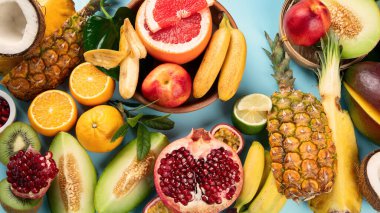 Mavi arka planda çeşitli taze meyveler. Vitaminler doğal beslenme konsepti. Üst görünüm.