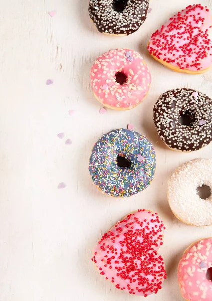 Donut deseni. Çeşit çeşit jöleli donutların üst görüntüsü. Kremalı renkli çörekler. Açık arkaplan üzerine serpiştirilmiş çeşitli renkli donutlar. Boşluğu kopyala.