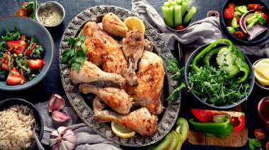 Pilavlı tavuk bacağı, sebze salatası ve koyu arkaplanda sos. Sağlıklı yemek konsepti. Üst görünüm.