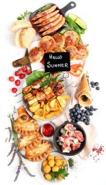 Yaz pikniği yemekleri, ızgara et, kebap, sebze salatası, meyve salatası, pizza, sandviç ve beyaz arka planda atıştırmalıklar. Üst görünüm.