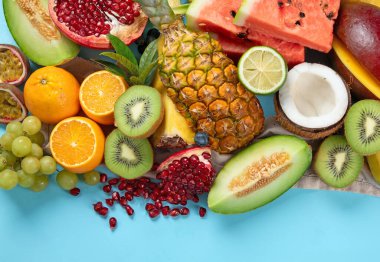 Mavi arka planda çeşitli taze meyveler. Vitaminler doğal beslenme konsepti. Üst görünüm.