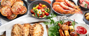 Yaz pikniği yemekleri, ızgara et, kebap, sebze salatası, meyve salatası, pizza, sandviç ve beyaz arka planda atıştırmalıklar. Üst görünüm.