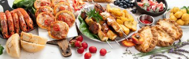 Yaz pikniği yemekleri, ızgara et, kebap, sebze salatası, meyve salatası, pizza, sandviç ve beyaz arka planda atıştırmalıklar. Üst Manzara. Panorama.