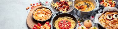 Gri arka planda eğlenceli bir Cadılar Bayramı parti masası sahnesi. Üst Manzara. Pizza, pasta, spagetti ve atıştırmalıklar. Kopyalama alanı olan Panorama