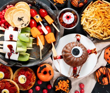 Gri arka planda eğlenceli bir Cadılar Bayramı parti masası sahnesi. Üst Manzara. Pizza, pasta, spagetti ve aperatif..