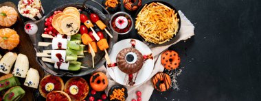 Gri arka planda eğlenceli bir Cadılar Bayramı parti masası sahnesi. Üst Manzara. Pizza, pasta, spagetti ve atıştırmalıklar. Kopyalama alanı olan Panorama.