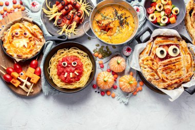 Gri arka planda eğlenceli bir Cadılar Bayramı parti masası sahnesi. Üst Manzara. Pizza, pasta, spagetti ve atıştırmalıklar. Boşluğu kopyala