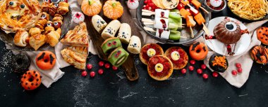 Gri arka planda eğlenceli bir Cadılar Bayramı parti masası sahnesi. Üst Manzara. Pizza, pasta, spagetti ve atıştırmalıklar. Kopyalama alanı olan Panorama.