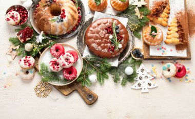 Beyaz arka planda çeşitli Noel tatlıları ve tatlılar. Üst Manzara. Pasta, çikolatalı pasta, kurabiye ve donut.