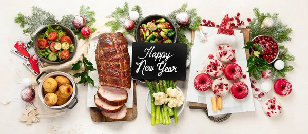 Concept of Christmas or New Year dinner with roasted meat and various vegetables dishes on a white background. Top view. Panorama.