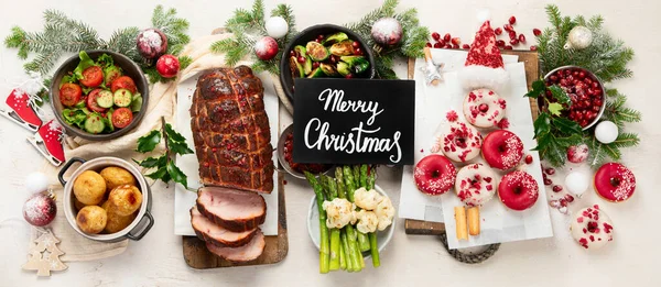 Concept of Christmas or New Year dinner with roasted meat and various vegetables dishes on a white background. Top view. Panorama.