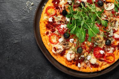 Domatesli, mantarlı ve salatalı sağlıklı kabuklu pizza. Karanlık bir arka planda masa sahnesi. Üst görünüm.