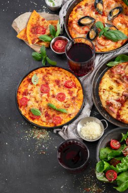 Pizza partisi yemeği. Üzerinde çeşitli İtalyan pizzası, salata ve kırmızı şarap bulunan bir masa.. 