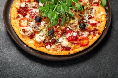 Domatesli, mantarlı ve salatalı sağlıklı kabuklu pizza. Karanlık bir arka planda masa sahnesi. Üst görünüm.