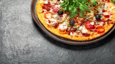 Domatesli, mantarlı ve salatalı sağlıklı kabuklu pizza. Karanlık bir arka planda masa sahnesi. Üst Manzara. Boşluğu kopyala.