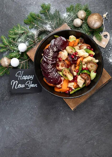 Baked, roasted, grilled vegetables in pan on a dark background. Beetroot, carrot, mushrooms, pumpkin and brussels sprouts. Christmas lunch, vegetarian Christmas dinner, top view. Copy space.