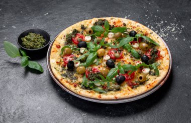 Siyah arka planda domatesli, peynirli, fesleğenli ve zeytinli pizza. Ev yapımı ince vejetaryen pizza. Üst görünüm.