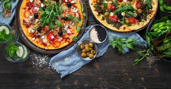 Pesto ve domates soslu İtalyan pizzaları. Siyah arka planda lezzetli vejetaryen pizzaları. Üst görünüm.