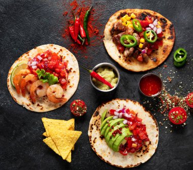 Salsa soslu taco, sebze ve siyah arka planda avokado. Üst görünüm, alanı kopyala.