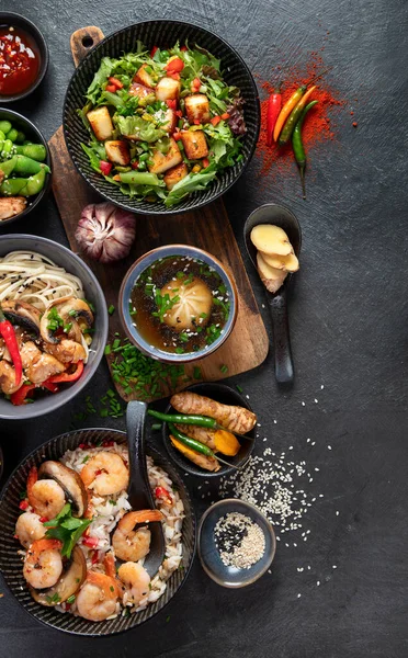 Asian food background with various ingredients on a black background, top view. Copy space.