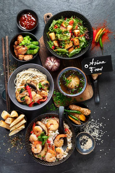 Asian food background with various ingredients on a black background, top view.