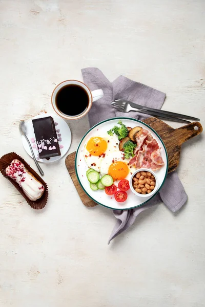 ベーコンストリップと伝統的なエングリスの朝食プレート 明るい背景に卵 ケーキの上の晴れた側面 — ストック写真