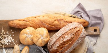 Beyaz arka planda çeşitli lezzetli taze pişmiş ekmek çeşitleri, üst manzara. Kopyalama alanı olan Panorama.