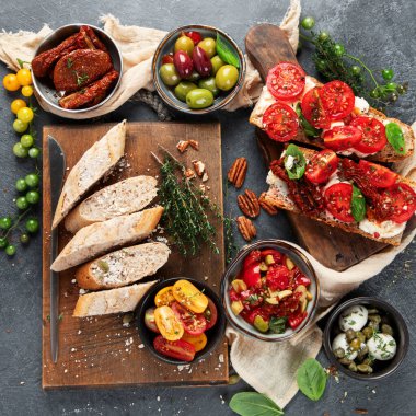 İtalyan antipasti aperatifleri. Peynirli lezzetli bruschettalar, güneşte kurutulmuş domatesler. Geleneksel gıda konsepti. Üst görünüm.