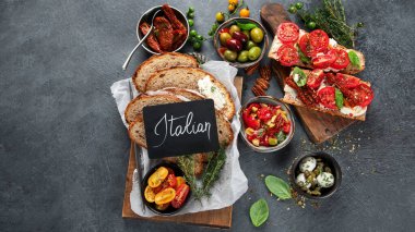 İtalyan antipasti aperatifleri. Peynirli lezzetli bruschettalar, güneşte kurutulmuş domatesler. Geleneksel gıda konsepti. Üst görünüm, alanı kopyala.