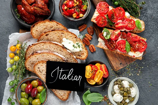 İtalyan antipasti aperatifleri. Peynirli lezzetli bruschettalar, güneşte kurutulmuş domatesler. Geleneksel gıda konsepti. Üst görünüm.