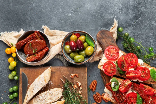 İtalyan antipasti aperatifleri. Peynirli lezzetli bruschettalar, güneşte kurutulmuş domatesler. Geleneksel gıda konsepti. Üst görünüm, alanı kopyala.