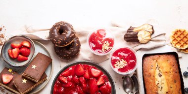 Hafif arka planda her türlü abur cubur olan tatlı masası. Çikolata. Kutlama konsepti. Üst Manzara. Kopyalama alanı olan Panorama.