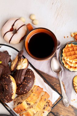 Bir fincan kahveli waffle, kurabiyeler, kek ve açık arkaplan. Sıcak içecek ve tatlılar. Üst görünüm, alanı kopyala.