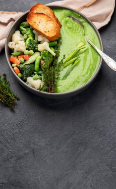 Yeşil sebze kremalı çorba gri arka planda gri bir kasede, üst manzara. Yeşil sebzeli vegan çorbası püresi. Vejetaryen ve diyet yemekleri. Boşluğu kopyala.