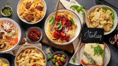 Makarna. İtalyan makarna yemekleri. Siyah arka planda spagetti bolonez, makarna, tortellini, ravioli ve diğerleri de var. Üst görünüm.