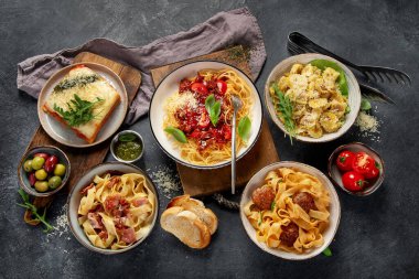 Makarna. İtalyan makarna yemekleri. Siyah arka planda spagetti bolonez, makarna, tortellini, ravioli ve diğerleri de var. Üst görünüm.