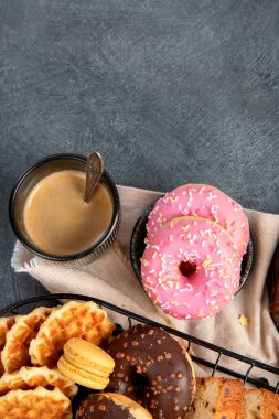 Lezzetli kurabiyeli beyaz kahve, çörek, kek, şeker, waffle. Karanlık arka planda şekerli sıcak içecek. Üst görünüm, alanı kopyala.