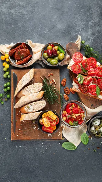 İtalyan antipasti aperatifleri. Peynirli lezzetli bruschettalar, güneşte kurutulmuş domatesler. Geleneksel gıda konsepti. Üst görünüm, afiş.