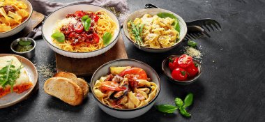 Makarna. İtalyan makarna yemekleri. Siyah arka planda spagetti bolonez, makarna, tortellini, ravioli ve diğerleri de var. Üst görünüm.
