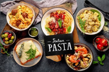 Makarna. İtalyan makarna yemekleri. Siyah arka planda spagetti bolonez, makarna, tortellini, ravioli ve diğerleri de var. Üst görünüm.